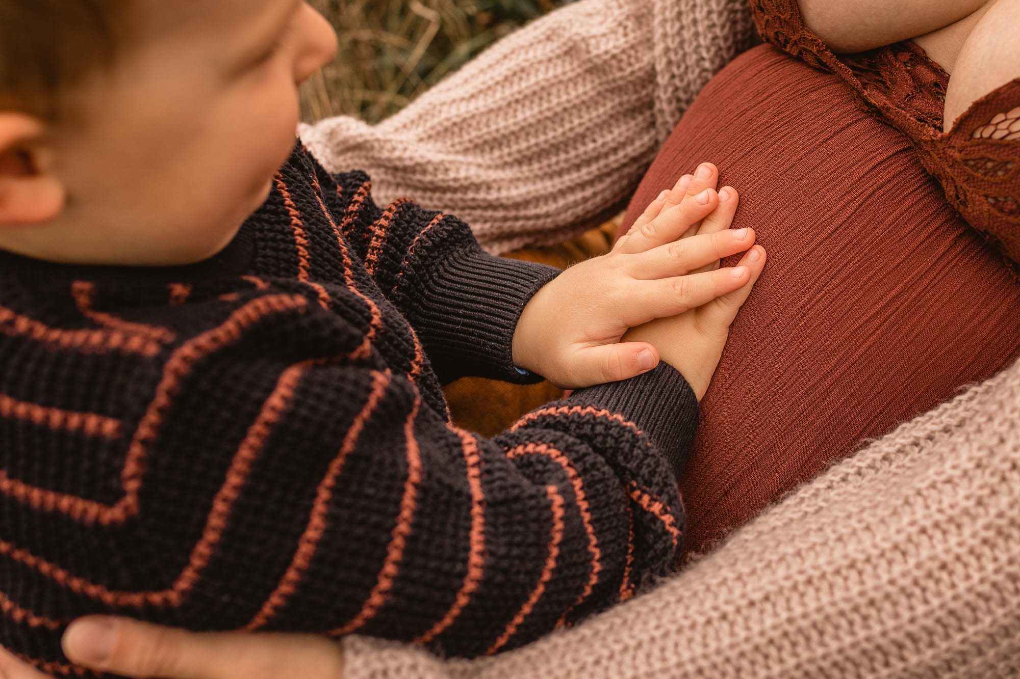 Kinderhände welche einen Babybauch berühren, anfassen