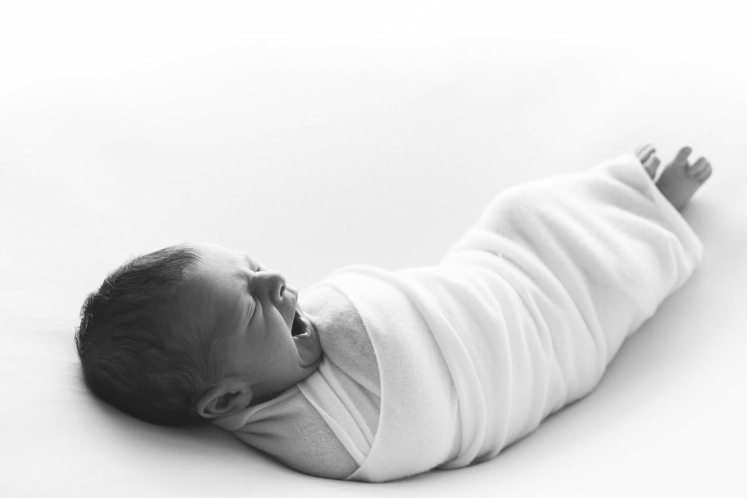 schwarz weiß Bild eines schlafenden Babies in einem Wrap gehüllt