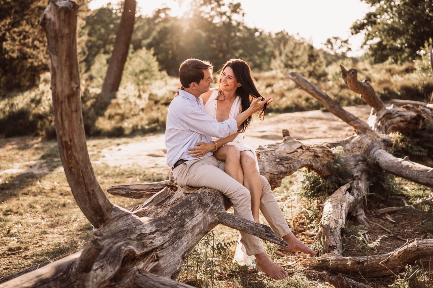 junges Paar auf einem alten liegenden Baumstamm eng sitzend