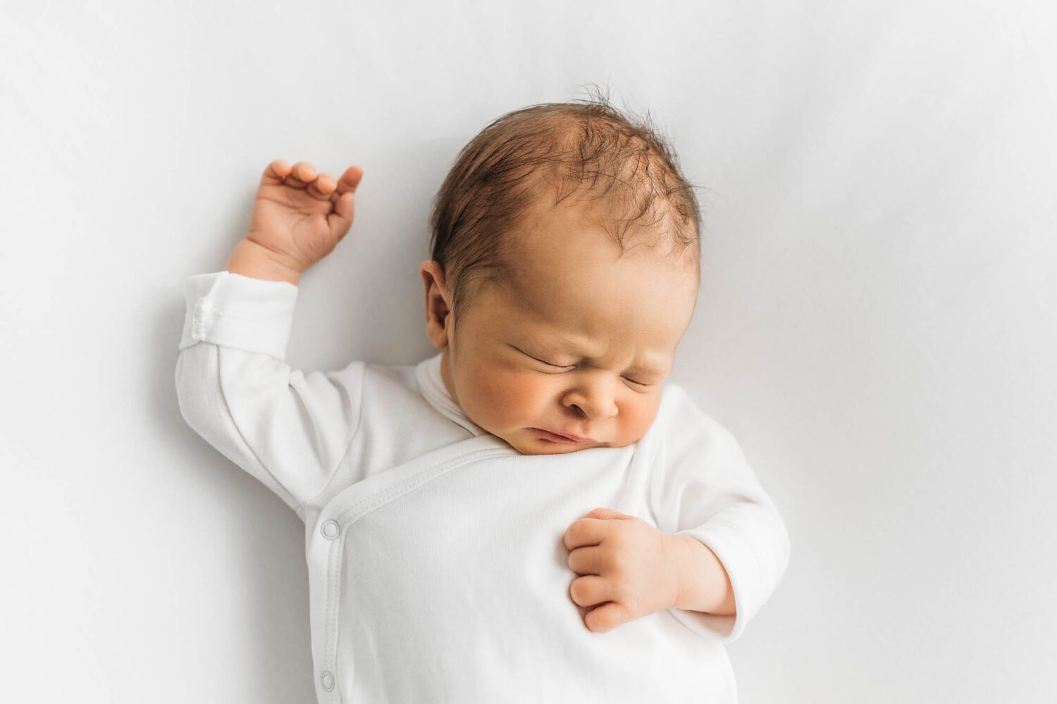 Neugeborenes Baby im Portrait schlafend auf dem Rücken liegend