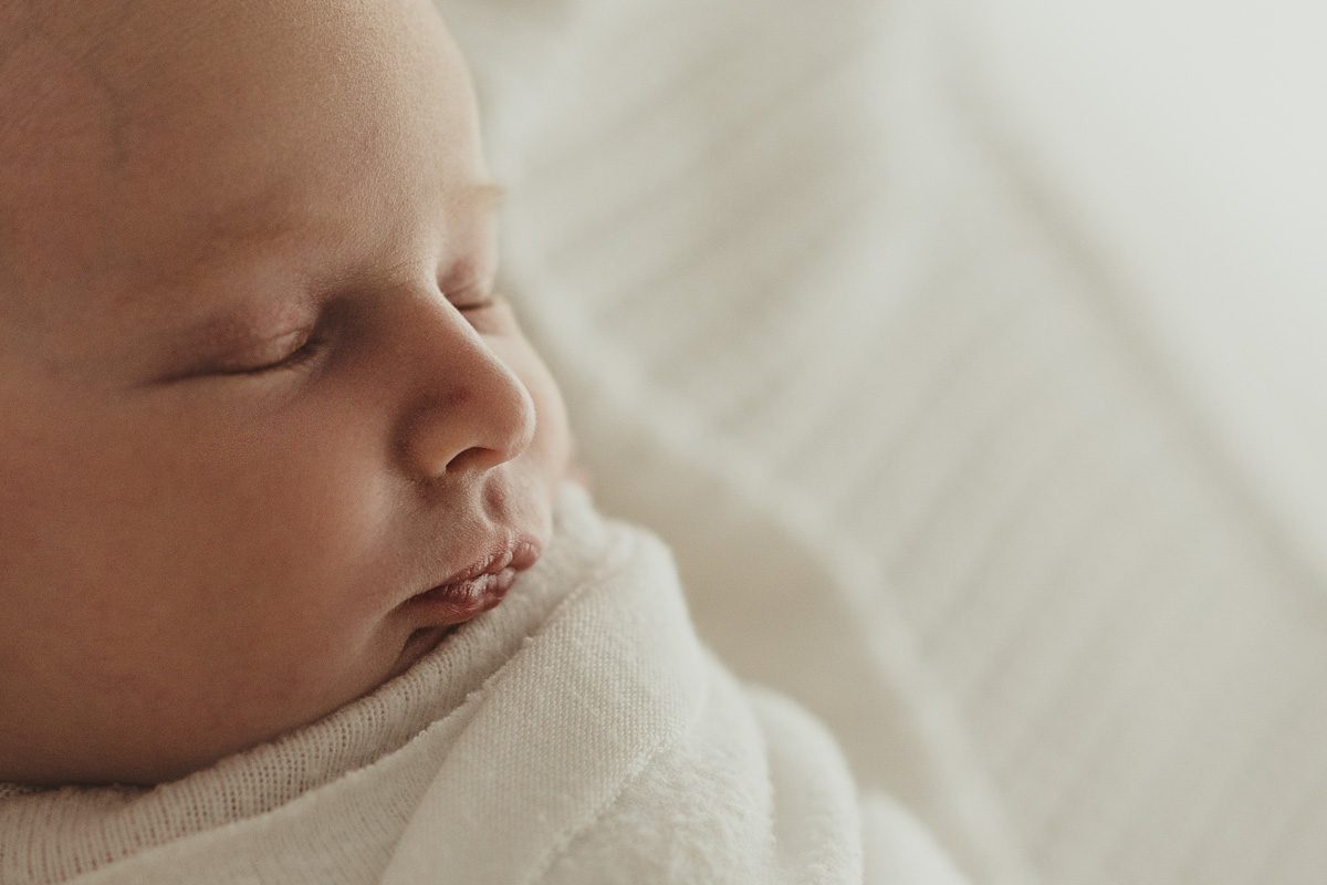 Nahaufnahme in schönem Licht vom Gesicht eines neugeborenen Mädchens, leicht seitlich fotografiert