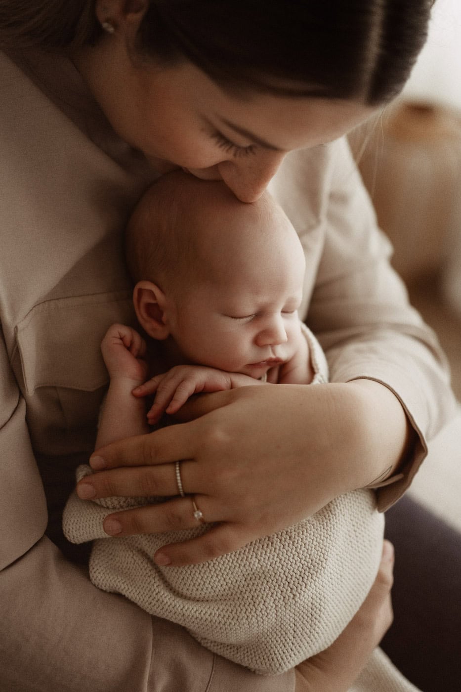 Sanfte Nahaufnahme eines schlafenden Babys, liebevoll gehalten von der Mutter, bei einem professionellen Baby- und Familienfotografen in Kerpen.