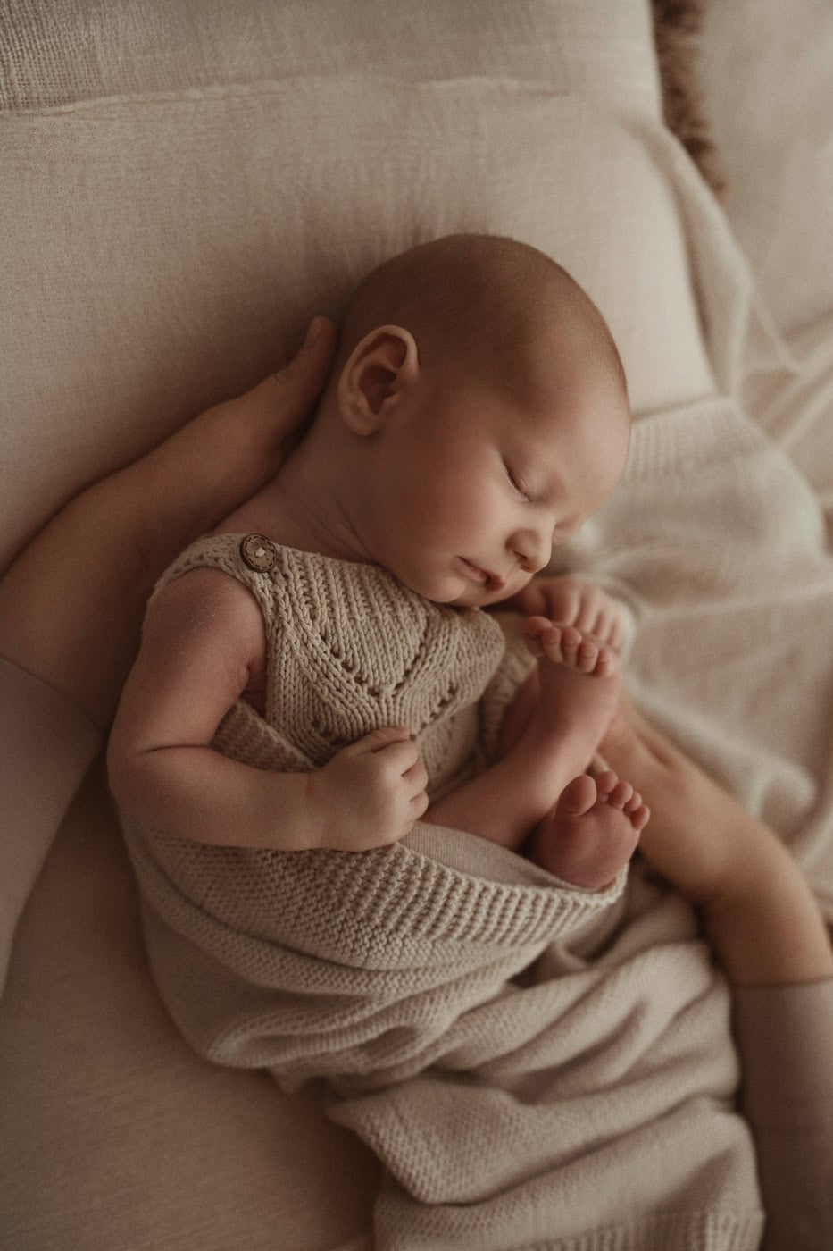 Sanftes Baby, das friedlich schläft, in warmen, bequemen Stoffen auf weicher Couch.